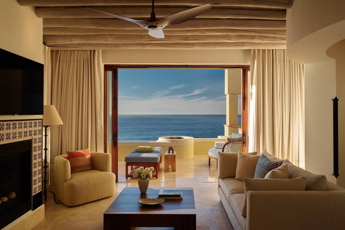 Un salón espacioso con vista al mar, chimenea y ventilador de techo.