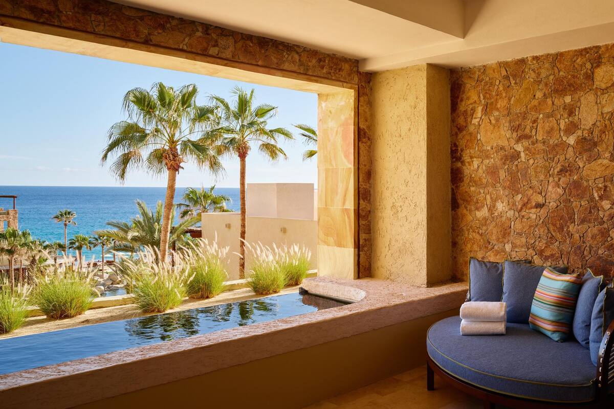 Una habitación con vista al océano, piscina y zona de estar también con vista.