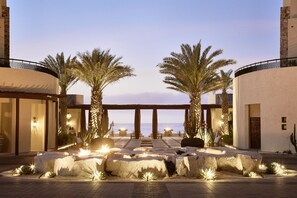 A resort entrance with palm trees, a pool area, and a view of the sea.