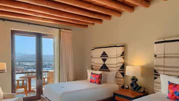 Una camera d'albergo con un letto grande, un tavolino, una sedia e vista sulla città da un balcone.