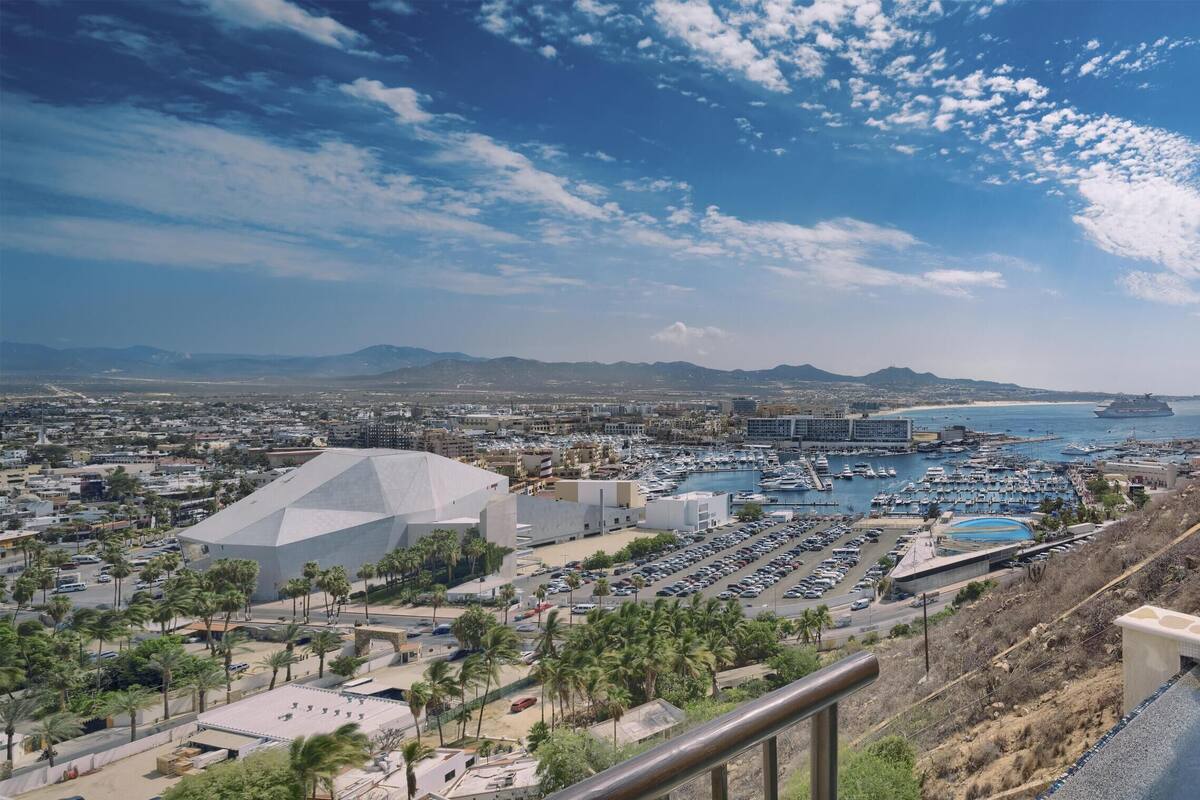 Un hotel con piscina, zona de descanso y vistas a un puerto deportivo y al paisaje urbano.