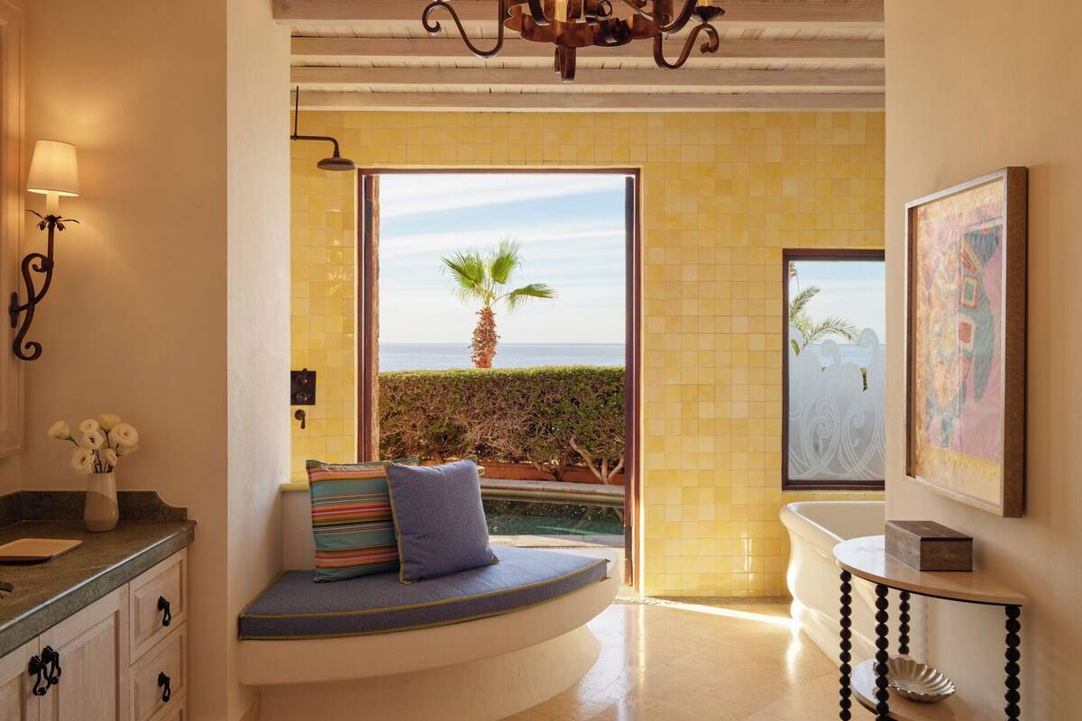Un baño moderno con bañera, una banca con vistas y un candelabro.