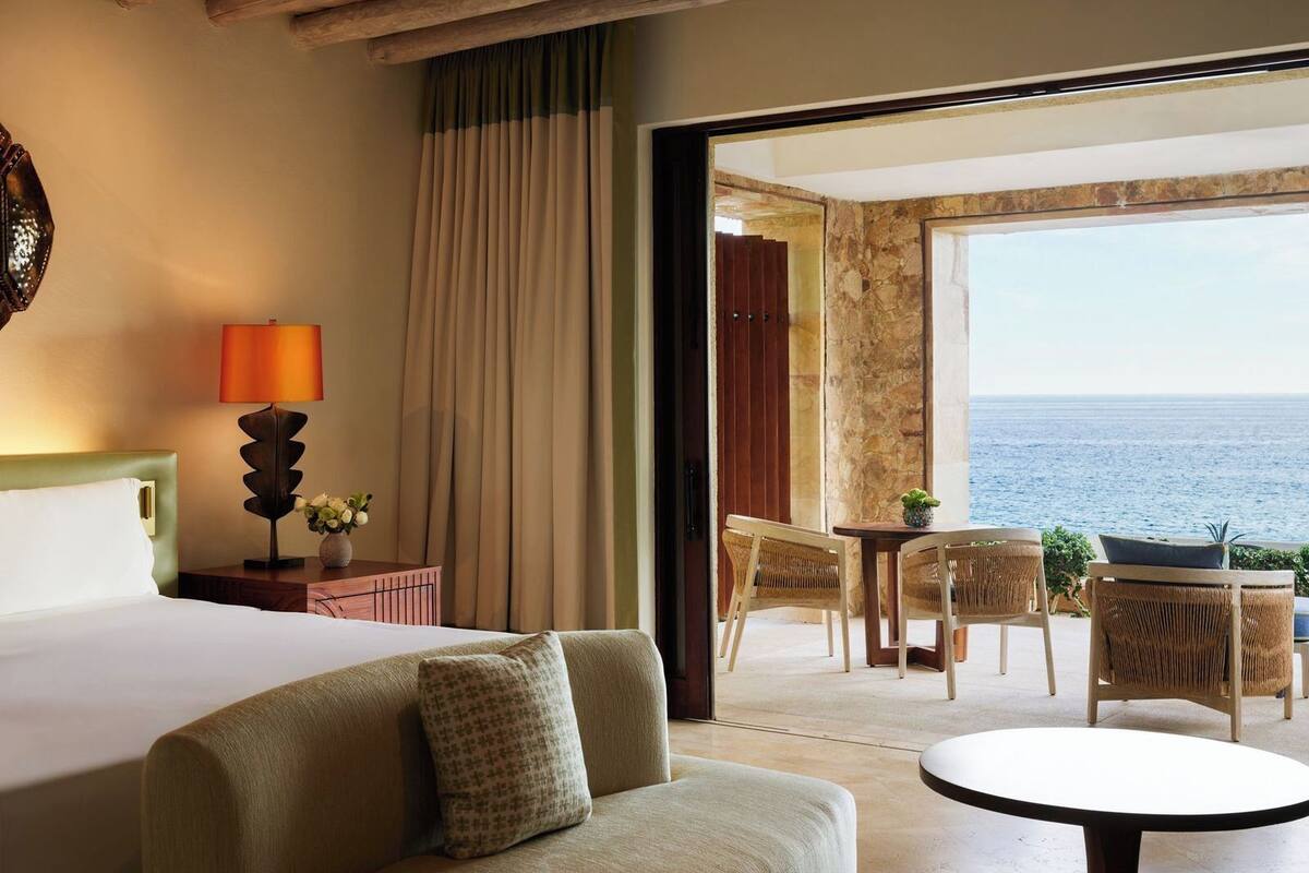 Habitación de hotel con una cama, un sofá, una mesa y vistas al mar.