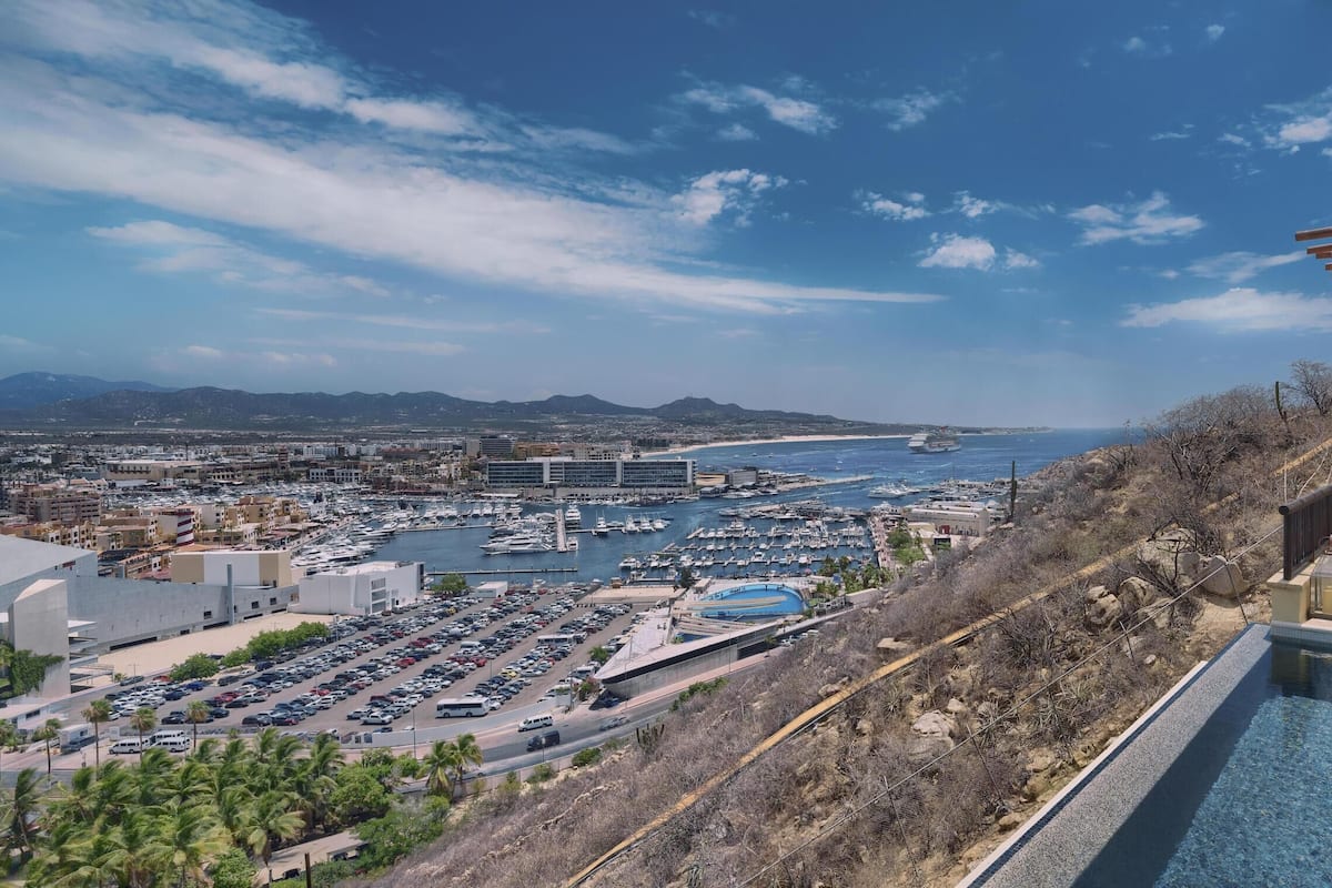Un hotel frente al mar con piscina, zona de estar exterior y vistas al puerto deportivo y la ciudad.
