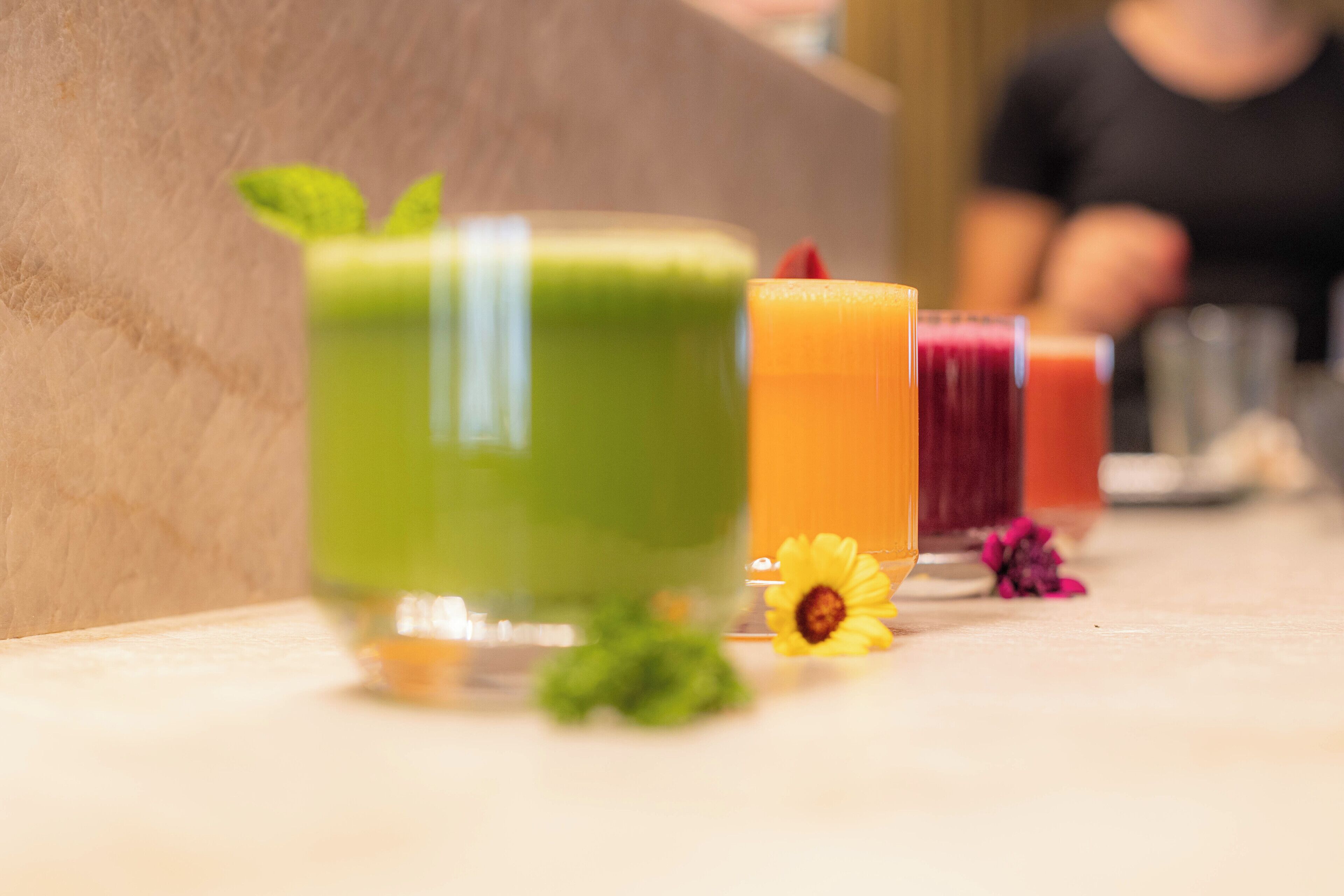 Una fila de bebidas coloridas sobre una mesa con un fondo desenfocado.