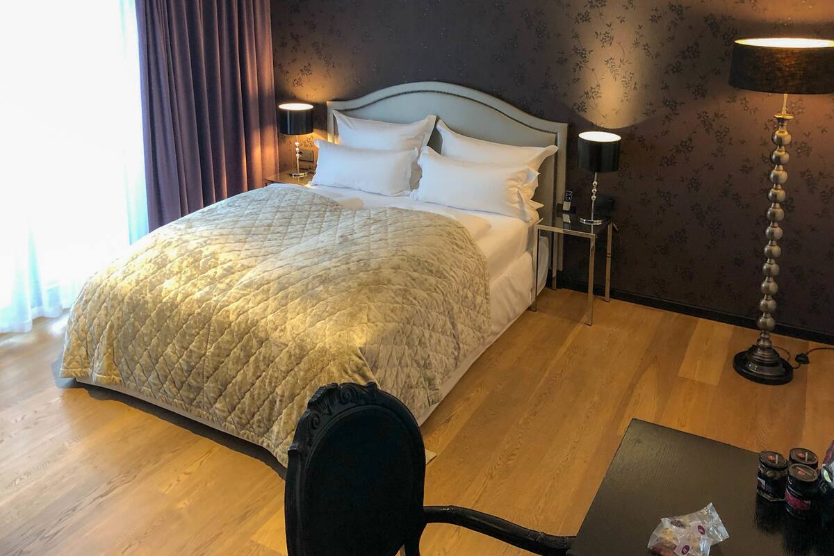 A hotel room with a large bed, two bedside tables, a lamp, and a chair.
