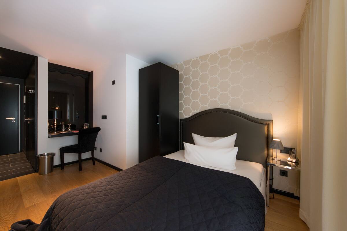 A hotel room with a large bed, a desk, and a chair.