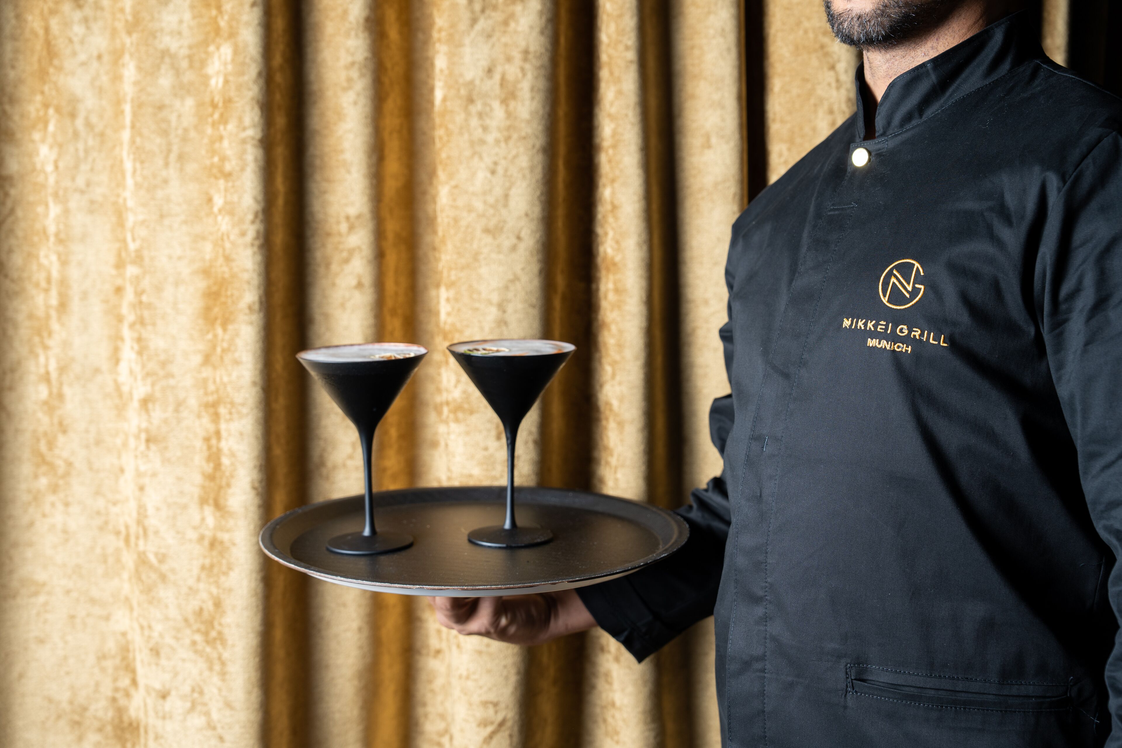 Une personne tenant un plateau sur lequel se trouvent deux verres à martini.