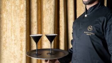 Une personne tenant un plateau sur lequel se trouvent deux verres à martini.