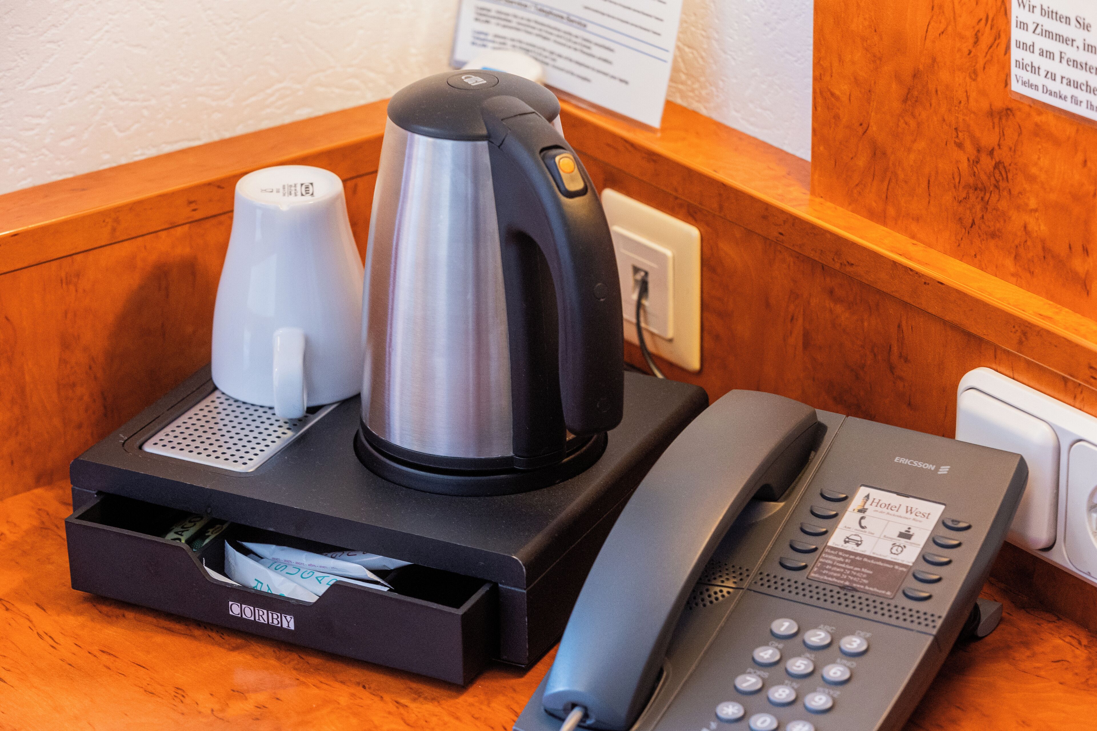 A hotel room with a coffee maker, a telephone, and a minibar.