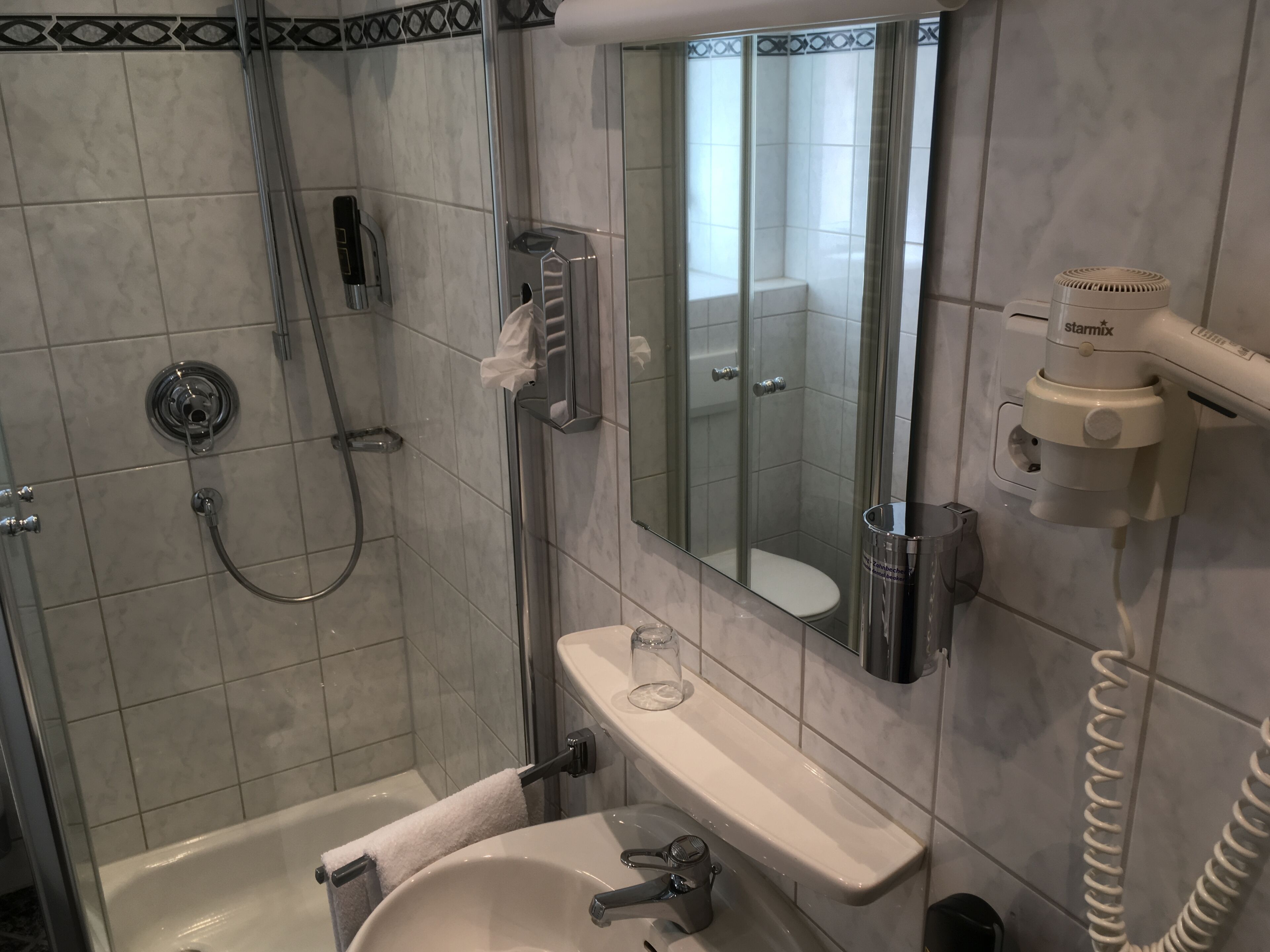 A modern bathroom with a glass-enclosed shower, a white sink, and a mirror.