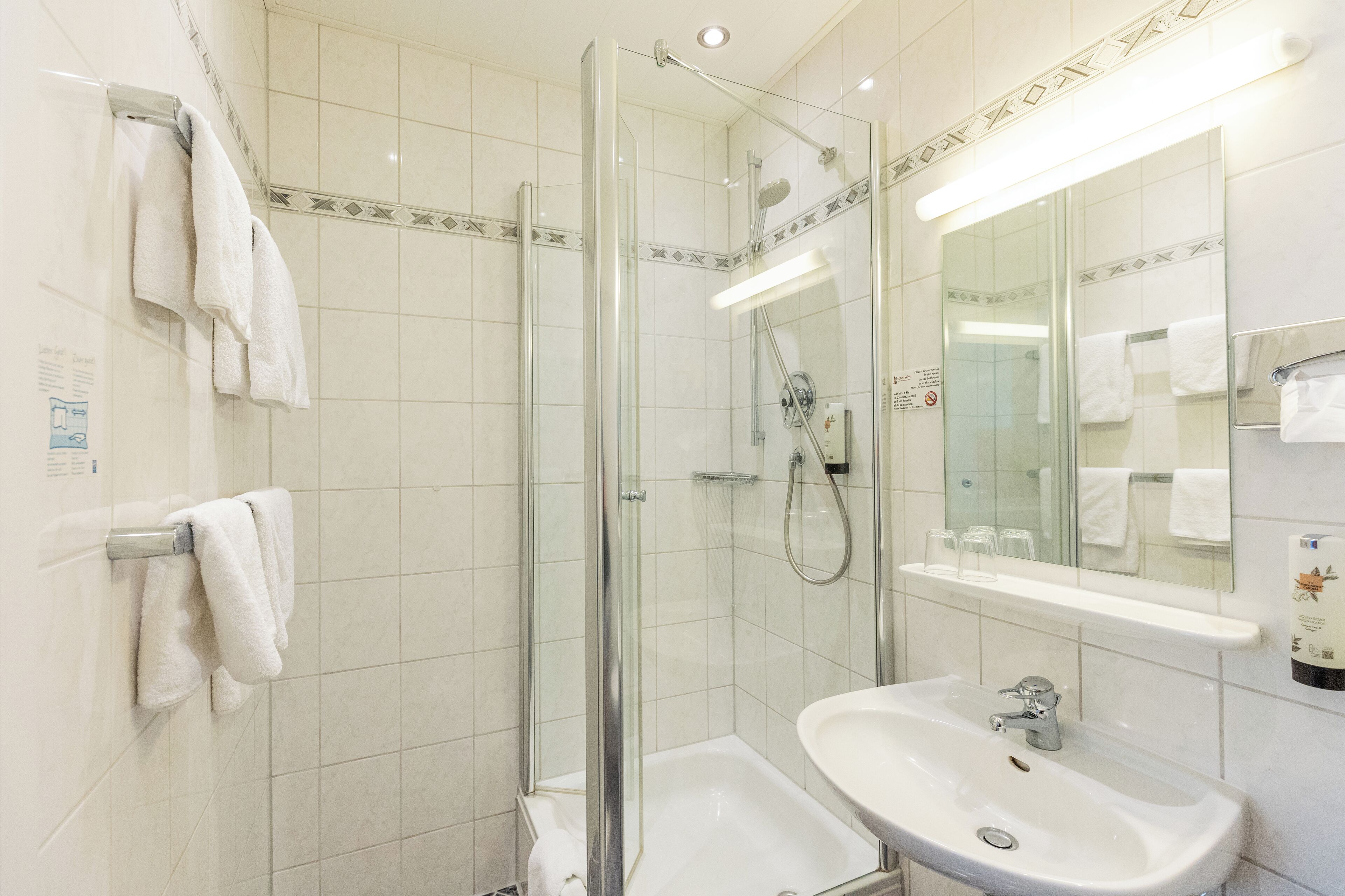 A modern bathroom with a glass-enclosed shower, a white sink, and a large mirror.