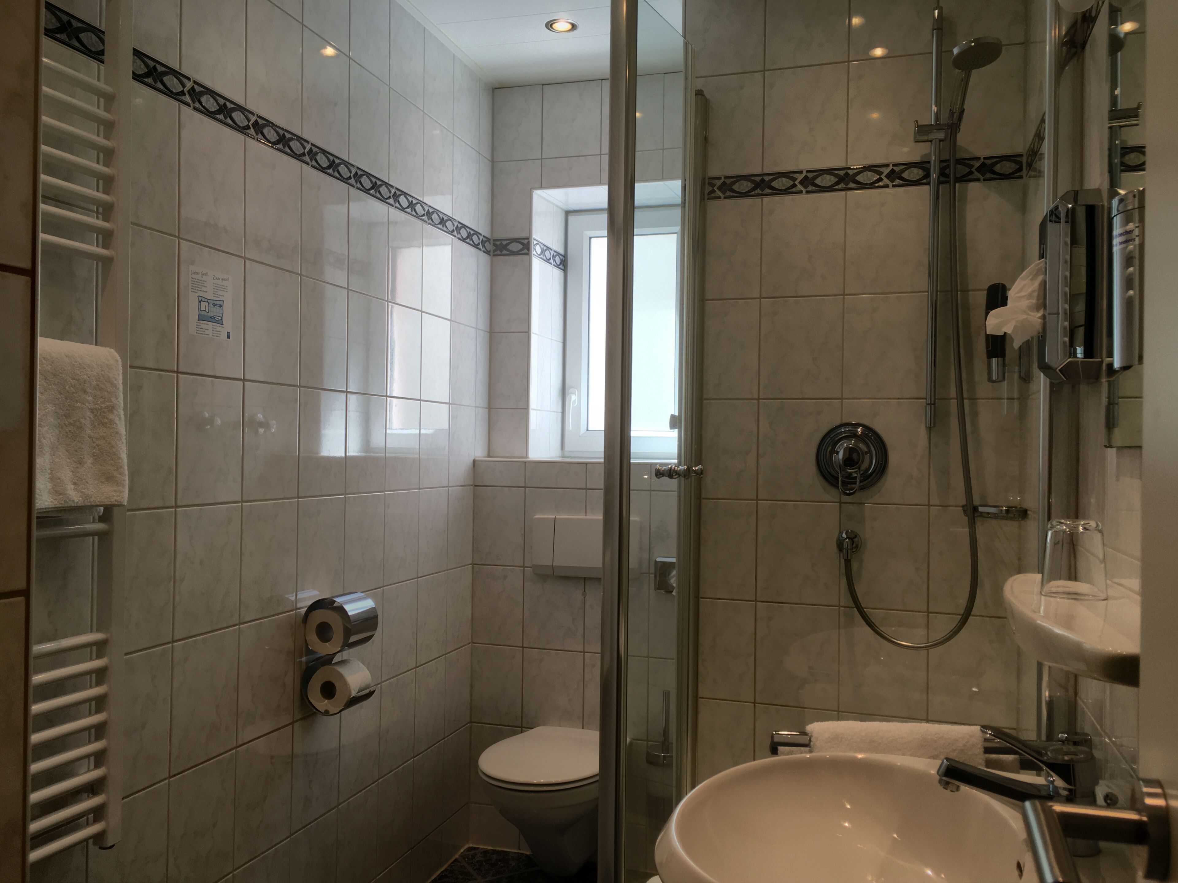 Un bagno moderno con cabina doccia in vetro, un lavandino bianco e un water.
