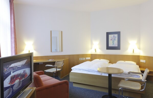 A hotel room with a bed, two bedside tables, a TV, a chair, and a desk. - Hotel Berliner Hof by Coffee Fellows Hotels (Kiel)