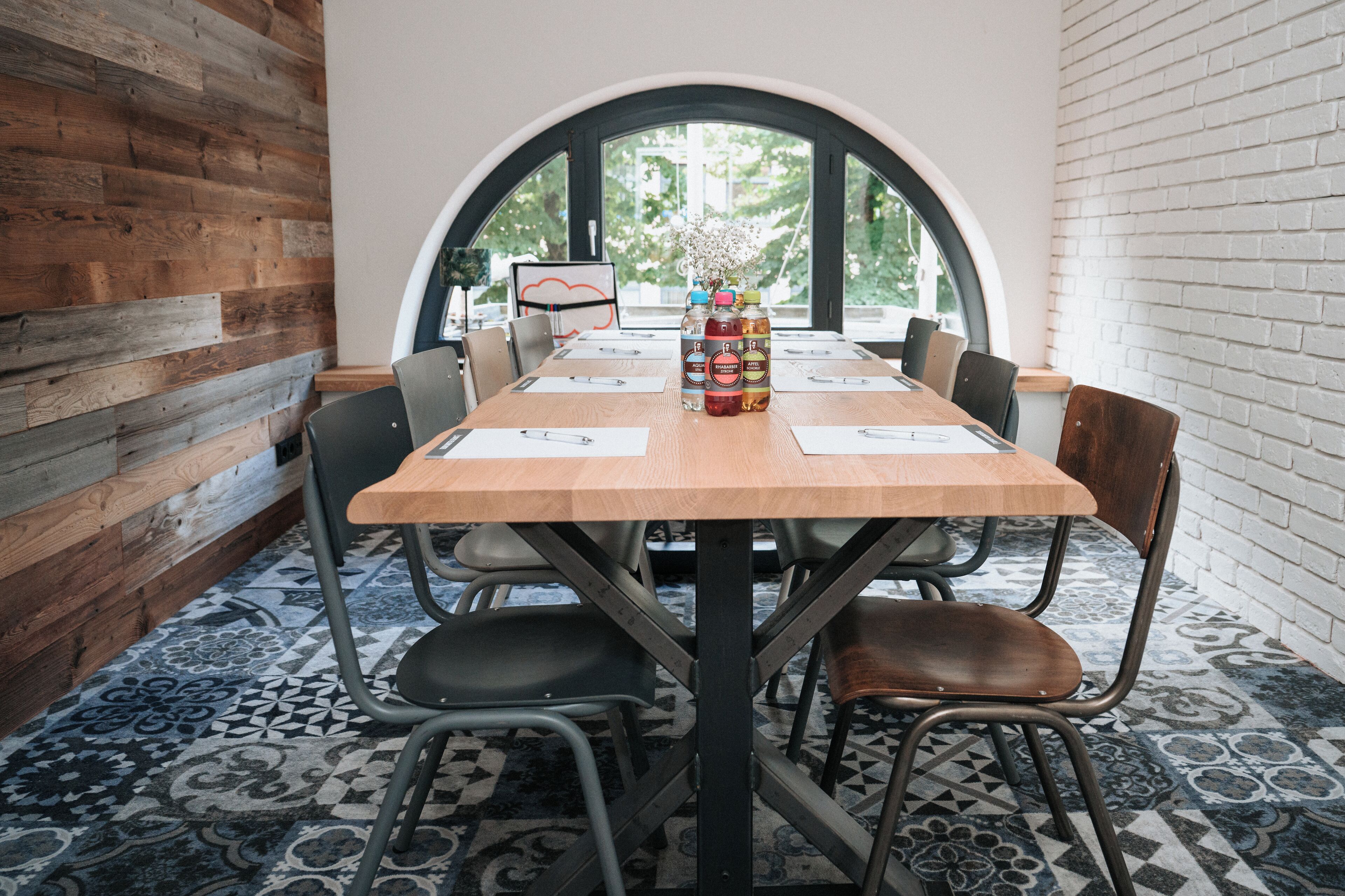 A conference room with a wooden table, black and brown chairs, and a patterned floor.