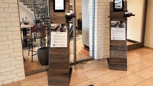A lobby with a brick wall, a reception desk, and a seating area with chairs and a table. - Hotel Berliner Hof by Coffee Fellows Hotels (Kiel)