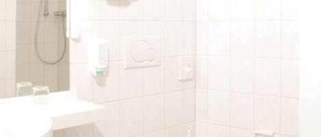 A small, white bathroom with a toilet, a sink, and a shower.
