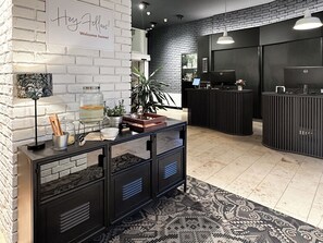 Un área de recepción con pared de ladrillo blanco, mostrador de recepción, mostrador negro y alfombra estampada.