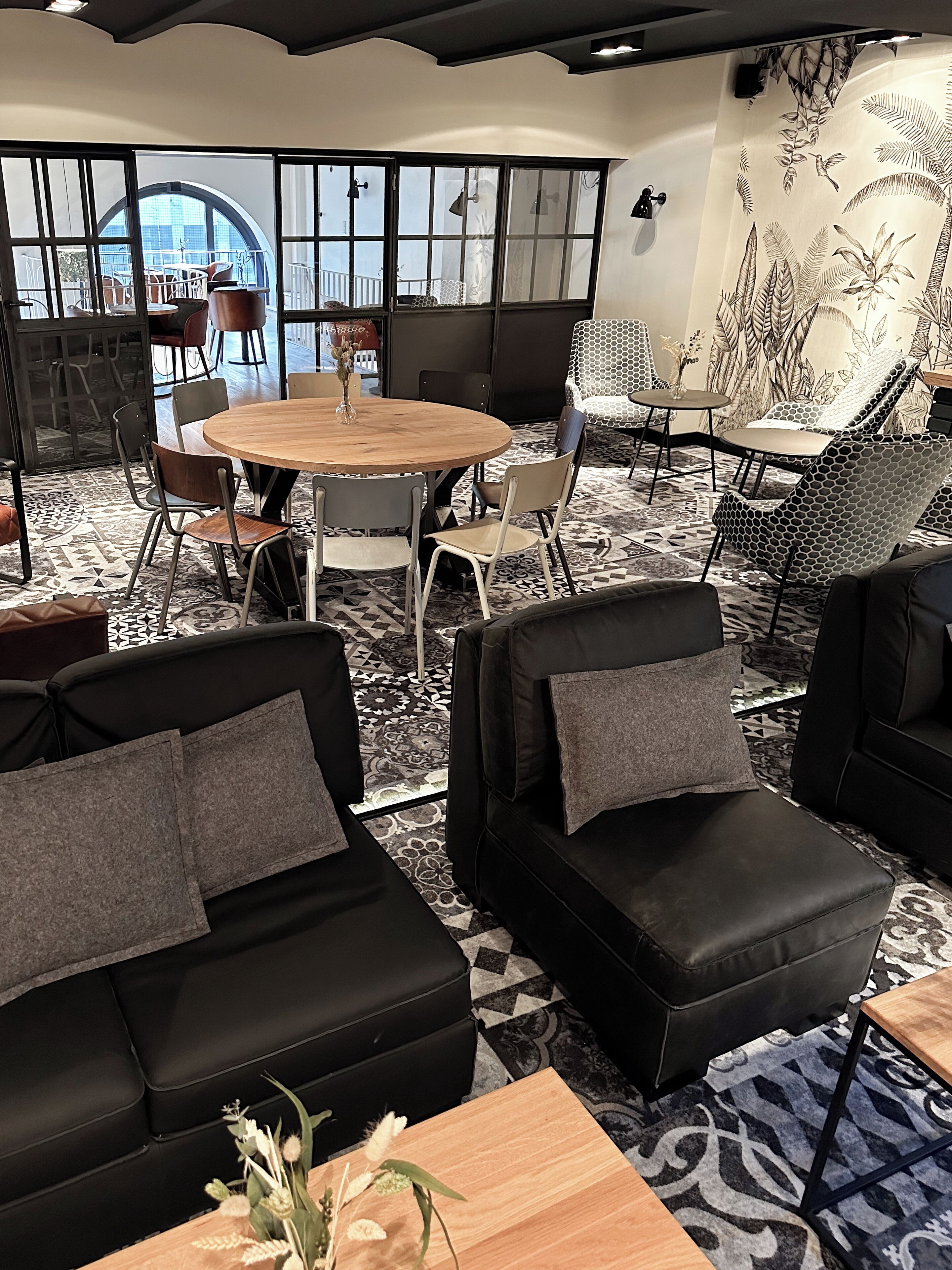Un'elegante area relax con divani in pelle nera, un tavolo rotondo in legno e un tappeto decorato.