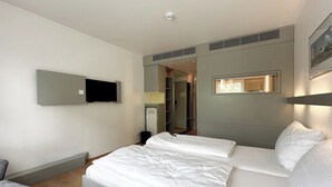 A modern hotel room with a large bed, a TV mounted on the wall, and a wardrobe. - Hotel Berliner Hof by Coffee Fellows Hotels (Kiel)