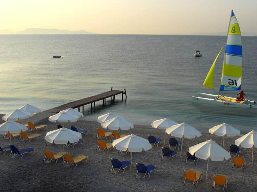 Na praia, espreguiçadeiras, guarda-sóis, prática de esqui aquático