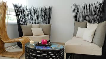Uma sala de estar moderna com um sofá, uma poltrona e uma mesa redonda com velas.