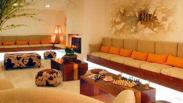 A modern living room with a sofa set, a coffee table with a chessboard, and a fireplace.
