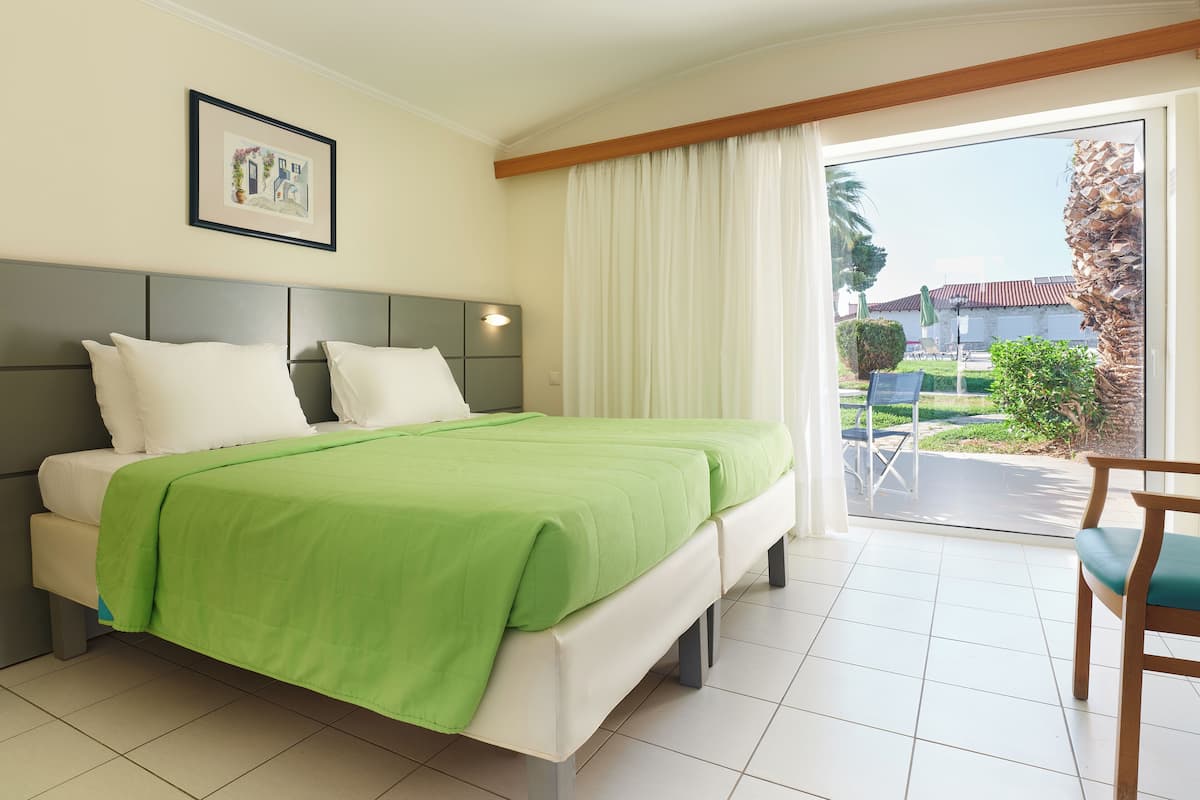 Quarto de hotel com uma cama, um quadro na parede, uma janela com cortinas e vista para o exterior.