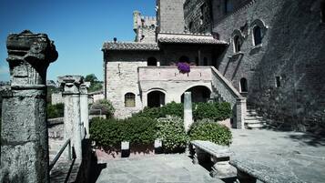 Un edificio histórico de piedra con ventanas de arco, una escalera y una maceta.