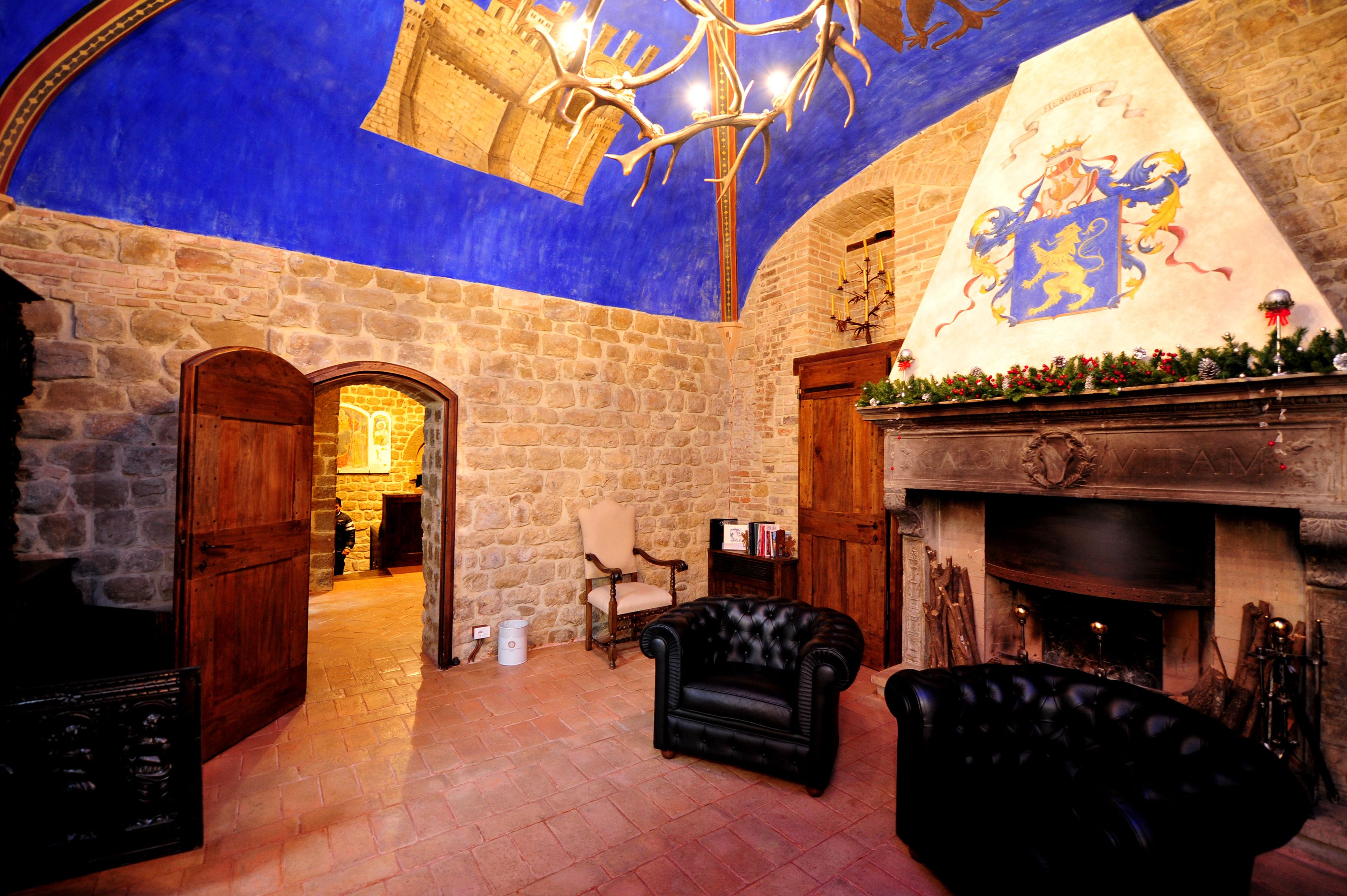 A stone-walled room with a fireplace, a chandelier, and a leather armchair.