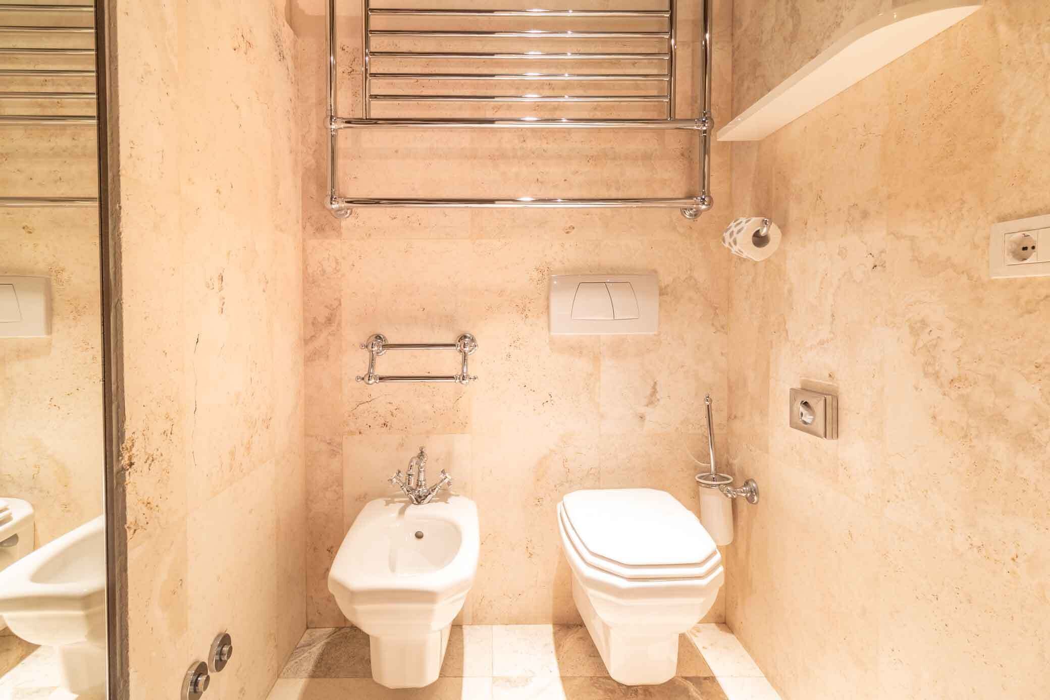 Un baño pequeño con bidé, inodoro y toallero.