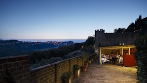 A stone pathway leading to a restaurant with outdoor seating, overlooking a scenic landscape. - TH Perugia - Castello di Monterone (Perugia)