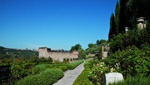 A stone pathway leading through a well-maintained garden with a view of a historic building in the distance. - TH Perugia - Castello di Monterone (Perugia)