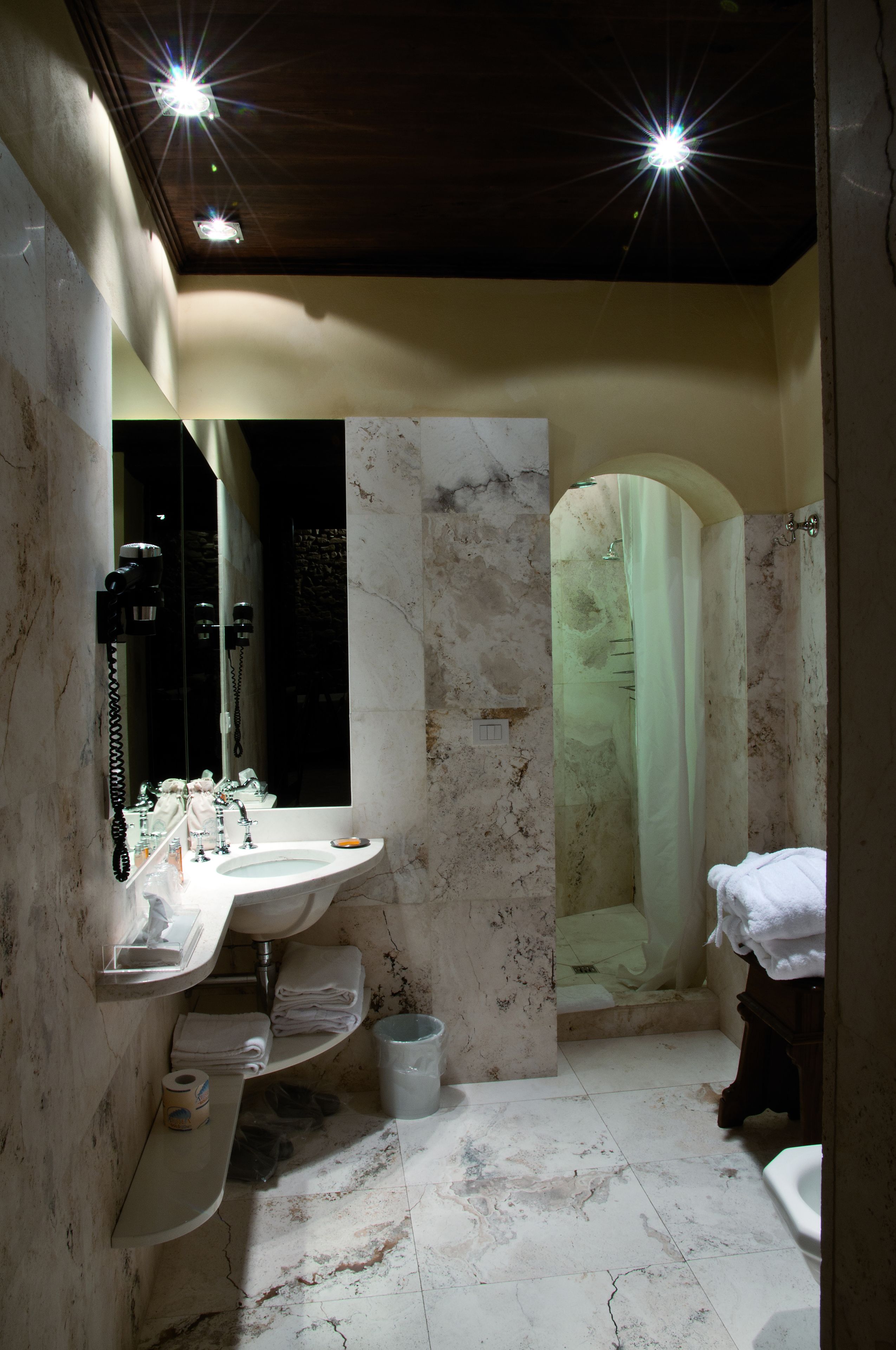 A bathroom with a marble sink, a large mirror, a shower with a curtain, and a toilet.
