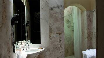 Une salle de bain avec un lavabo en marbre, un grand miroir, une douche avec un rideau et des toilettes.