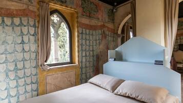A bedroom with a bed, a window with curtains, and a decorative wall with a scalloped pattern.