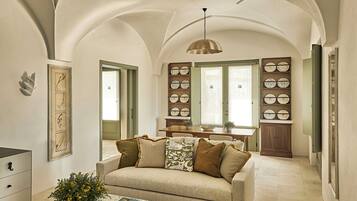 Un ampio soggiorno con soffitto ad arco, una zona pranzo con tavolo e sedie, e una cucina con pensili e una lampada a sospensione.