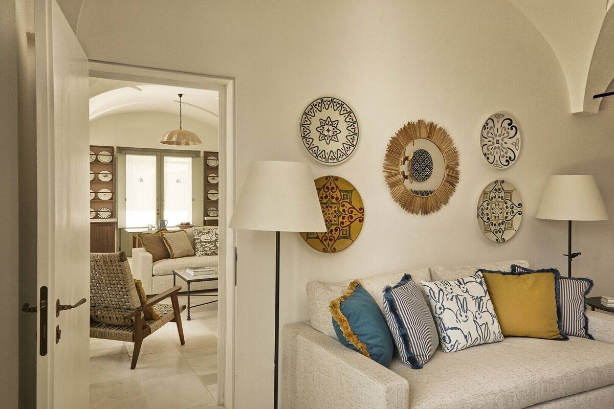 Ein Interieur mit einer Sofagarnitur, dekorativer Wandgestaltung und einer Lampe.