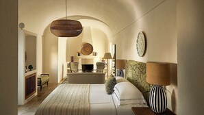 A spacious bedroom with a large bed, a hanging light fixture, and a fireplace. - Rocco Forte Masseria Torre Maizza (Fasano)