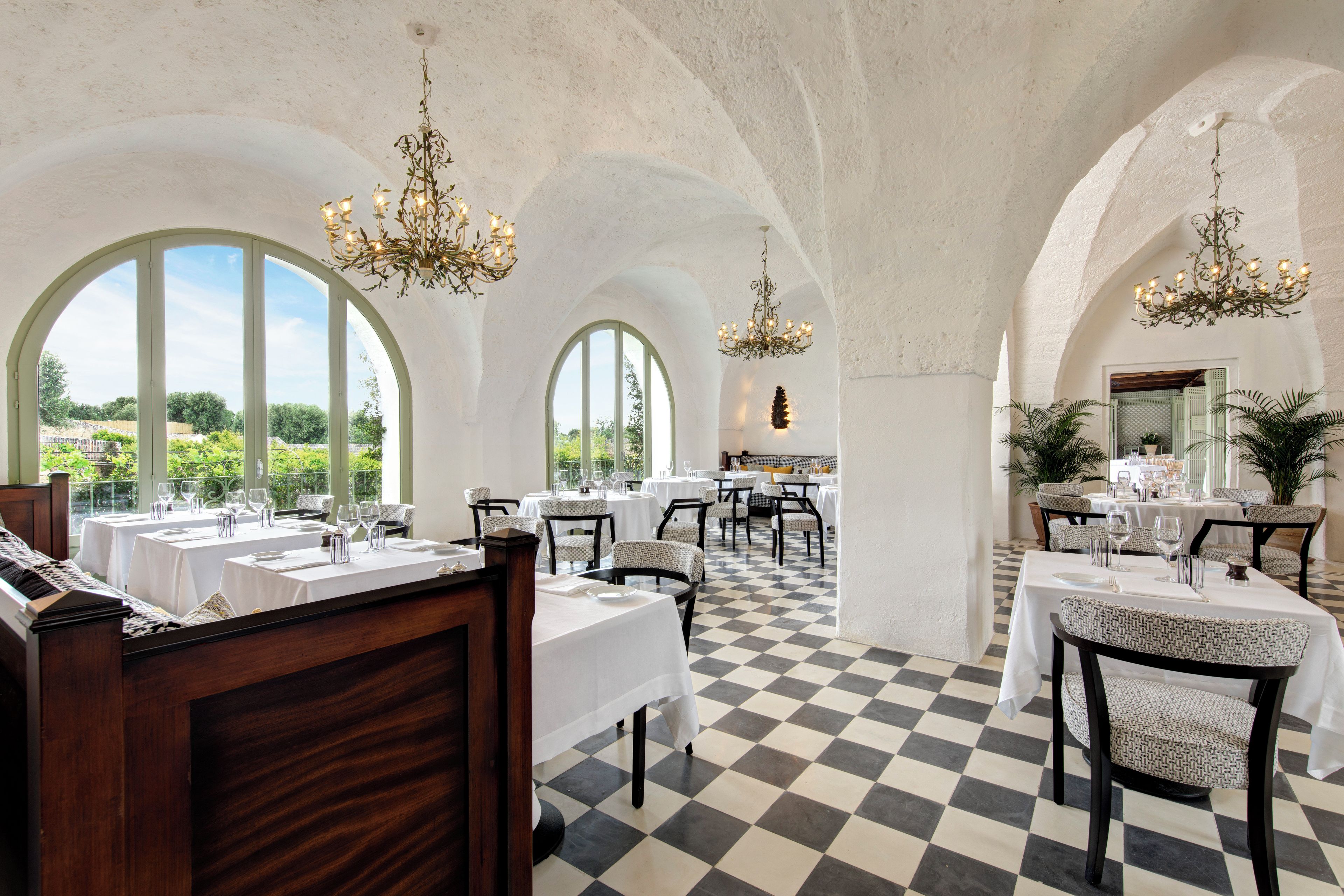 Zona pranzo con pavimento a scacchi, tavoli imbanditi e soffitti a volta.