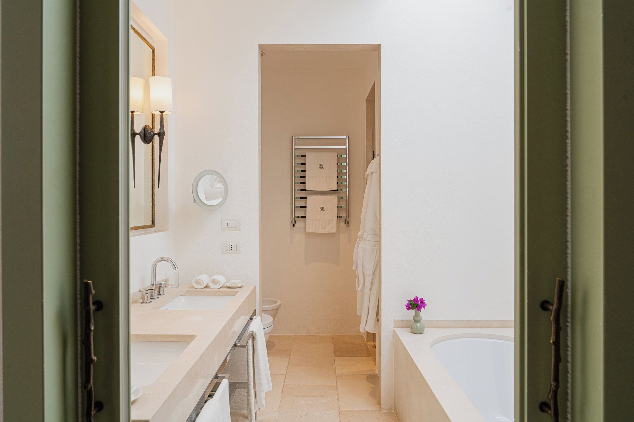 A modern bathroom with a sink, mirror, towel rack, and bathtub.
