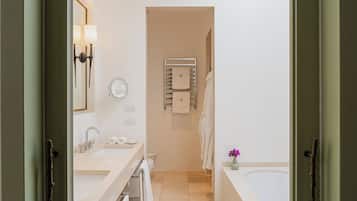 A modern bathroom with a sink, mirror, towel rack, and bathtub.