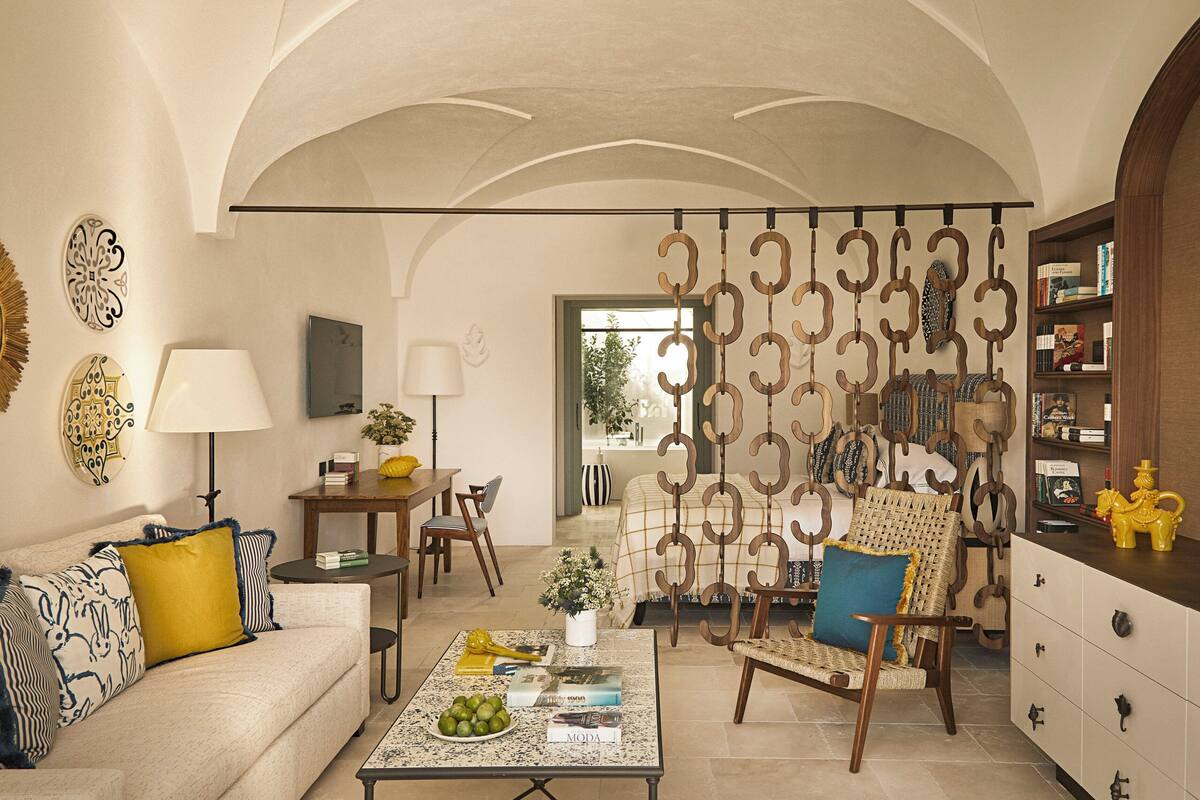 A spacious living room with a high ceiling, a dining area, and a seating area with a decorative wall.