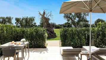 Een terras met een ontbijttafel, lounge stoelen en een grote parasol.
