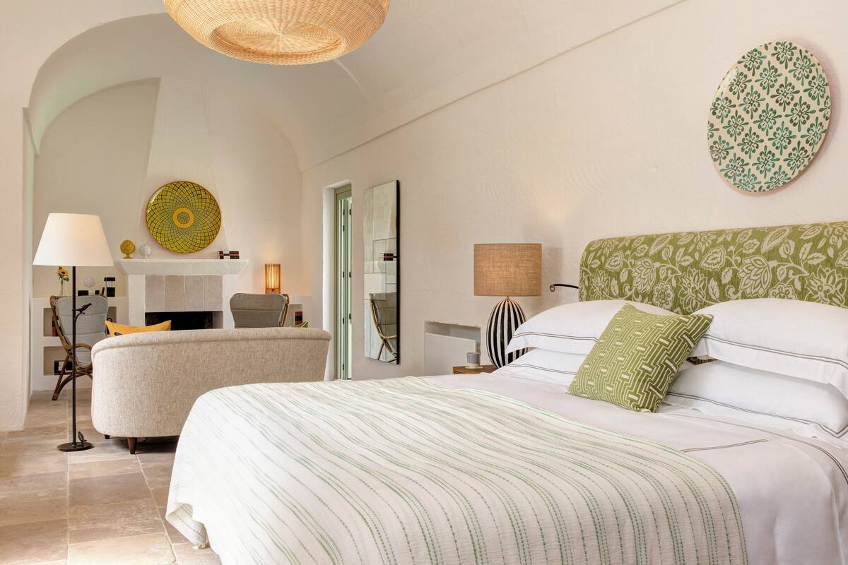 Ein Hotelzimmer mit einem großen Bett, einer Sitzecke mit einem Sessel, einem kleinen Tisch und einem Kamin.
