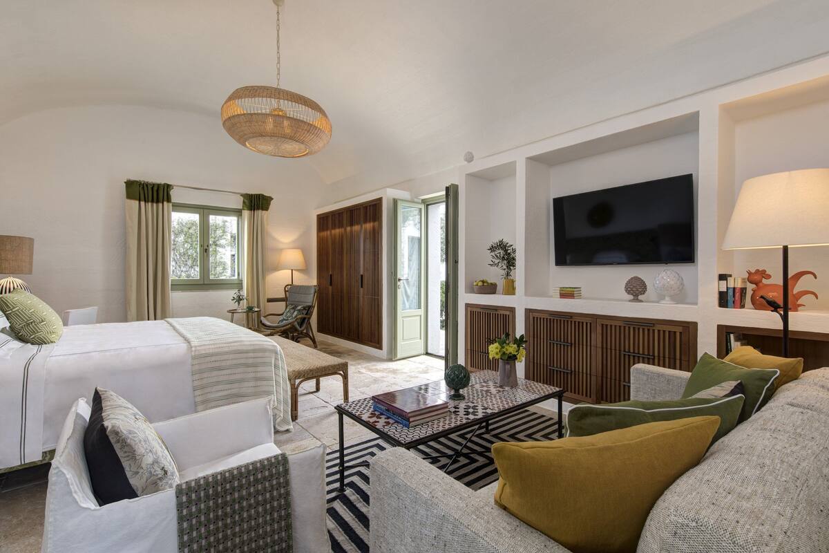 Ein Hotelzimmer mit Bett, Sofa, Couchtisch, Fernseher und Lampe.