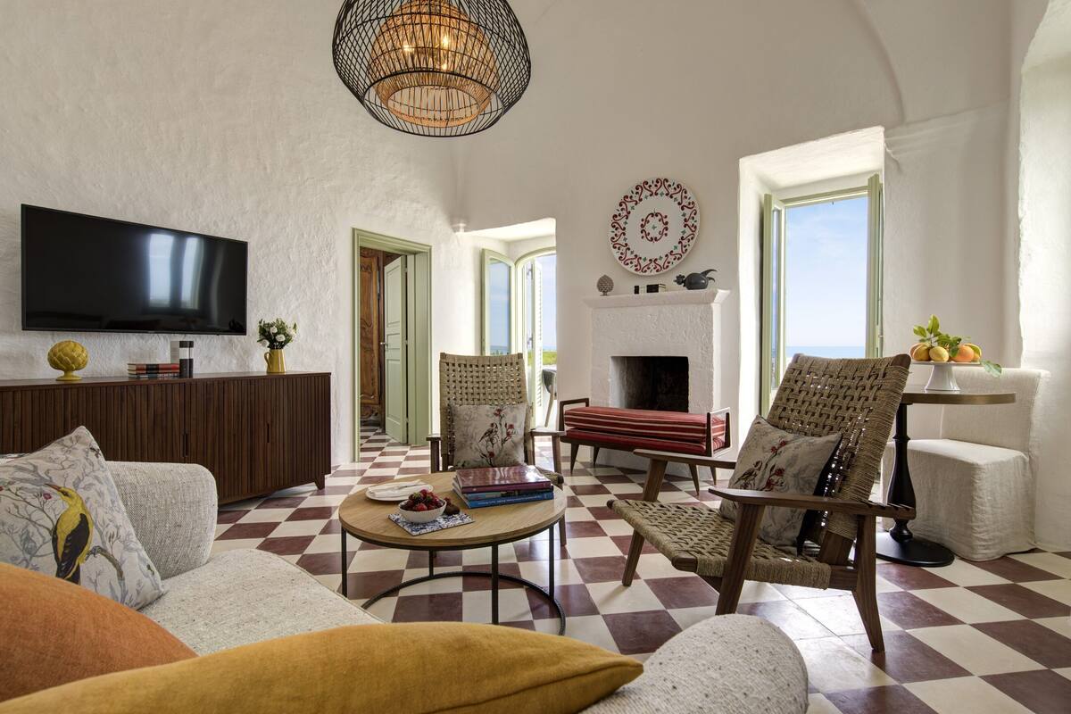 A living room with a checkered floor, a flat-screen TV, a fireplace, and a large window.