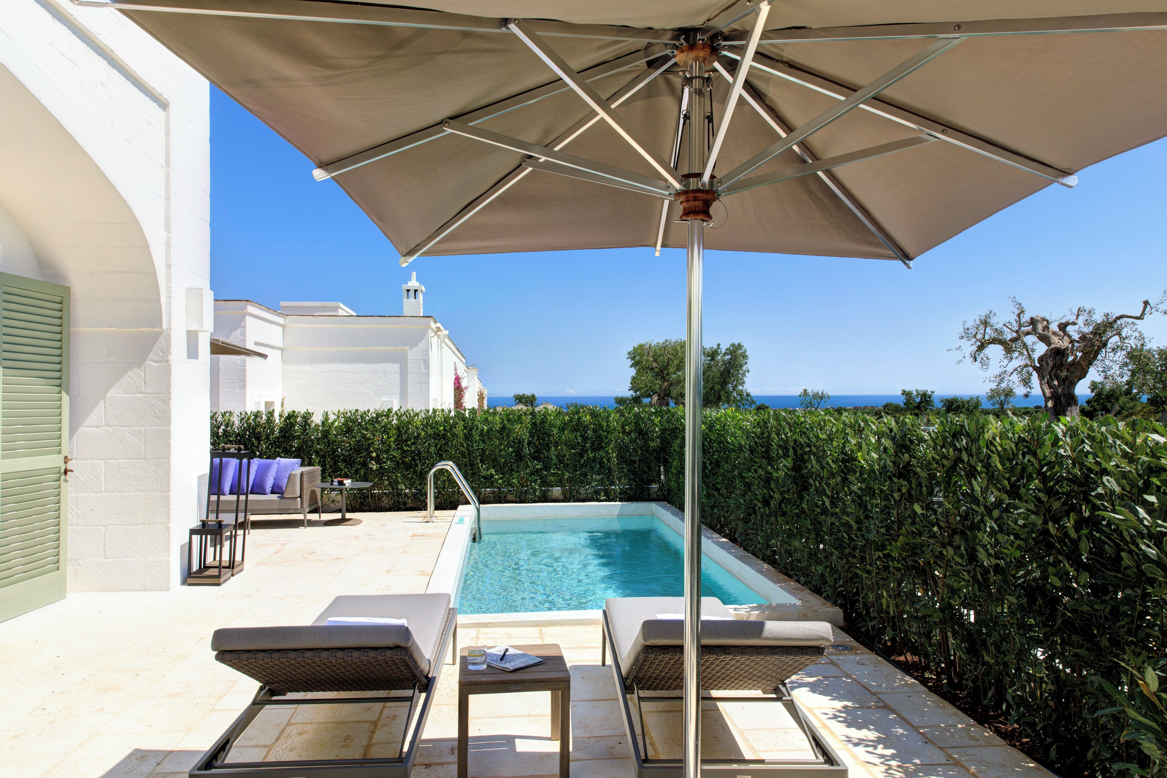 A poolside area with lounge chairs, a table, and an umbrella.