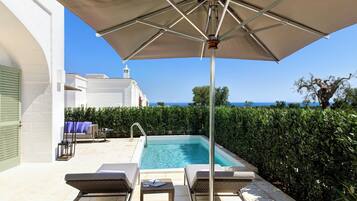 A poolside area with lounge chairs, a table, and an umbrella.