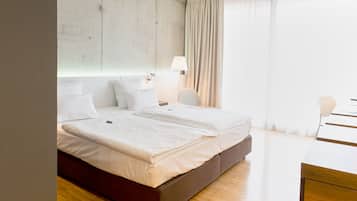 Quarto de hotel com uma cama grande, uma escrivaninha, uma luminária e vista para o exterior.